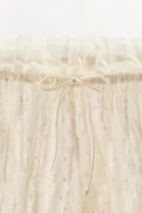 Shorts de tiro medio y cintura elástica ajustable con cordones, confeccionados en tejido plumeti con detalles de frunces y terminaciones con volados en el bajo.