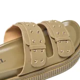 Sandalia mule verde con plataforma texturizada tipo crepe, dos tiras superiores con hebillas cuadradas y tachas metálicas decorativas.