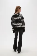 Sweater de tejido jacquard con diseño de rayas irregulares en tonos negro, blanco y gris. Presenta cuello redondo a la base, mangas largas y un corte holgado.