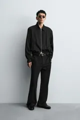 Cazadora bomber negra con textura arrugada, cuello solapa, hombreras marcadas, manga larga con puño abotonado, bolsillos de vivo en la cadera, bajo elástico y cierre frontal con cremallera.