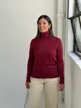 Polera de punto color bordó con cuello alto, manga larga y puños acanalados.