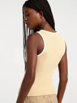 Musculosa de tejido acanalado en color amarillo claro, con cuello redondo y sisas con ribete en color blanco en contraste.