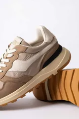 Championes urbanos de diseño técnico, combinando paneles de gamuza y tela en tono verde oliva con detalles en beige y negro. Presentan una suela de plataforma en color crema con base dentada en tono caramelo.