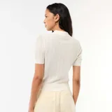 Remera de punto calado de manga corta en color blanco, con cuello polo y cierre frontal de botones.