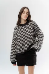 Buzo de punto grueso con diseño bicolor en patrón geométrico, de calce holgado y mangas largas.