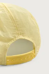 Gorra de 5 paneles de color amarillo claro con tejido ripstop, visera plana marrón de efecto desgastado y bordado frontal en negro. Cuenta con ajuste en la parte posterior.