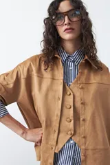 Sobrecamisa de gamuza color marrón, de silueta relajada, con cuello camisero, botones frontales y bolsillos de parche en el pecho.