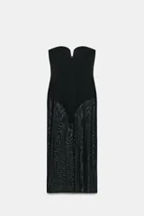 Vestido largo negro de diseño strapless con escote corazón y abertura frontal. Presenta un forro interior tipo body y falda de tul transparente con textura.