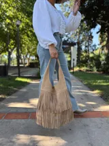 Cartera tipo hobo de cuero color beige con flecos en dos niveles.