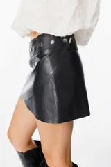 Mini falda tipo cruzada confeccionada en cuero, con detalle de cintura con tachas metálicas.