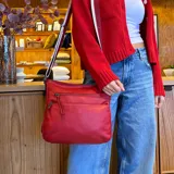 Bandolera de cuero sintético color mostaza, con dos bolsillos frontales con cierre, apertura superior con cierre, división interna y bolsillo trasero con cierre. Incluye correa larga regulable combinada en tonos mostaza y beige.