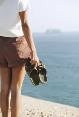 Sandalias planas color ladrillo, con doble tira ancha sobre el empeine y plantilla anatómica. Fabricadas en Brasil con materiales veganos y procesos sostenibles.