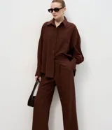Pantalón sastre de corte wide leg en tejido crepé color marrón chocolate. Presenta una silueta recta y fluida, con cintura elástica y lazo ajustable para un calce cómodo.