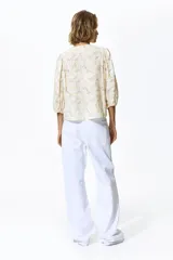 Blusa en tejido liviano de mezcla de lino, de color blanco con estampado floreado. Cuenta con cuello redondo, cierre frontal de botones y mangas globo tres cuartos con puños elásticos.