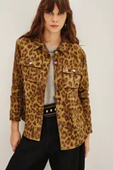 Campera de canvas con estampado animal print de leopardo, corte recto, cuello camisero, cierre frontal con botones metálicos y bolsillos frontales con solapa.