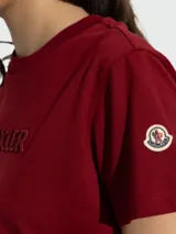 Remera Moncler de manga corta y cuello redondo, color bordó, con el nombre de la marca bordado en relieve en el pecho.