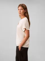 Blusa de manga corta Calvin Klein en color blanco marfil, confeccionada en tejido de crepé de chine. Presenta un diseño de corte regular con cuello en V adornado con un detalle de barra metálica horizontal.