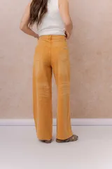 Jean de calce relajado y pierna amplia color beige, con tiro alto y detalle de recortes y costuras visibles.