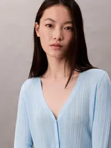 Cardigan de punto canalé con acabado brillante, cuello en V y cierre frontal con botones. Presenta un diseño de manga larga y corte ajustado.