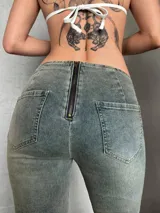 Pantalón de jean con lavado ácido, corte acampanado y tiro bajo. Presenta un cierre frontal con cordones ajustables y detalles de tachas metálicas a lo largo de las costuras verticales frontales.