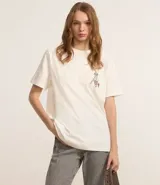Remera de algodón color crudo con cuello redondo y mangas cortas. Estampa frontal pequeña y estampa trasera grande de Tom y Jerry.