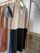 Vestido largo estilo túnica de algodón con diseño bicolor, cuerpo en tono tostado y parte inferior negra, de manga corta y cuello redondo.