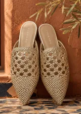 Sandalias tipo mule de punta fina y diseño destalonado. Presentan capellada tejida en tono dorado con patrón geométrico entrelazado.