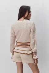 Sweater calado de algodón color celeste, con cuello redondo, mangas largas y diseño cómodo. Presenta puños, cintura y terminaciones acanaladas con rayas en contraste de color marrón.