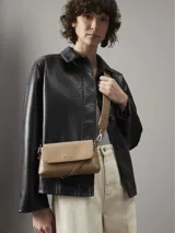 Cartera bandolera Calvin Klein color beige con monograma en relieve. Tiene correa ajustable, cierre de cremallera y logo de la marca en el frente.