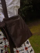 Chaleco de cuero marrón con diseño estructurado que incluye arnés en la espalda y dos bolsillos laterales amplios con bolsillos internos.