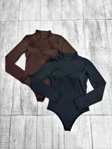 Body de manga larga con cuello alto tipo polera, confeccionado en tela elástica. Cuenta con copas integradas en el busto y cierre inferior.
