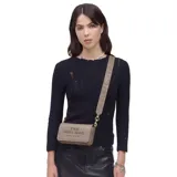 Cartera bandolera Marc Jacobs modelo The Mini Bag, confeccionada en cuero premium color beige. Presenta diseño rectangular con solapa frontal, logo grabado en el frente y correa ajustable con el nombre de la marca tejido.