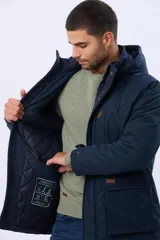 Campera de abrigo color azul marino, con capucha desmontable, cierre frontal con solapa, bolsillos frontales con solapa y detalle de etiqueta de cuero sintético. Cuenta con interior forrado en corderito en la parte superior para mayor calidez.