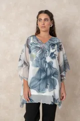 Blusa tipo túnica de gasa semitransparente con escote en V. Presenta un diseño fluido con estampado artístico de flores en tonos azules y grises sobre fondo blanco.