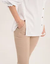 Pantalón chupín color beige de gabardina elastizada con tajitos frontales en el ruedo, pierna recta justa y bolsillos laterales.