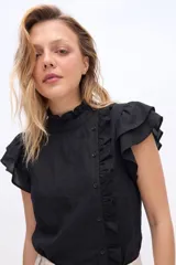 Blusa de manga corta con volados en los hombros, cuello alto con ribete fruncido y cierre frontal desplazado con botones y detalle de volado.