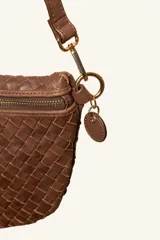 Bandolera de gamuza color marrón con diseño de media luna, decorada con tachas metálicas doradas distribuidas en el frente. Cuenta con cierre superior metálico y correa larga ajustable para llevar cruzada.