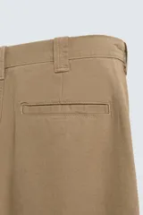 Pantalón chino de corte recto confeccionado en tejido ligero de algodón con estructura canvas. Presenta bolsillos frontales, bolsillos traseros de vivo y cierre frontal con cremallera y botón.