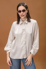 Camisa de seda color crema con cuello clásico, cierre frontal de botones y mangas largas con puños abotonados.