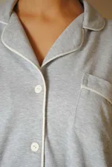 Conjunto de pijama de algodón gris con estampado geométrico blanco, compuesto por una camisa de manga larga con botones y un pantalón largo con elástico en la cintura.