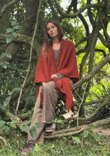 Ruana color ladrillo con detalle de trenzado en el cuello y flecos en el borde inferior.