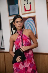 Vestido midi con estampado abstracto en tonos fucsia, rosa y violeta. Presenta un diseño de cuello halter cruzado con detalle de collar integrado y espalda descubierta.
