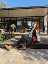 Chaleco negro con interior de corderito, con detalles en color naranja y ribeteado en marrón.