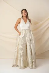 Vestido largo de fiesta color champagne, con corpiño tipo corsé de crepe de seda y falda amplia de organza con lurex dorado. Incluye bolsillos laterales.