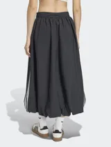 Falda larga de estilo deportivo con silueta voluminosa tipo globo, confeccionada en tejido técnico color negro. Presenta el diseño clásico de tres rayas blancas laterales y el logo del trébol bordado. Cuenta con cintura elástica y cierre lateral.