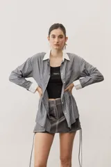 Camisa de rayas grises y blancas, de corte oversize, con cuello y puños anchos en contraste de color blanco, manga larga y bolsillo aplicado en el pecho.