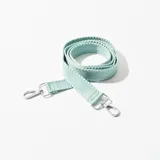 Correa de tela color verde agua con mosquetones plateados en los extremos para sujetar a una cartera.