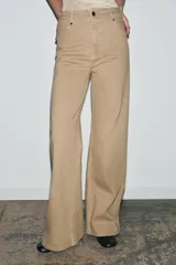 Jeans de tiro alto con corte wide leg y largo completo. Presenta diseño de cinco bolsillos, trabillas en la cintura y cierre frontal con cremallera y botón, con un acabado de efecto lavado.
