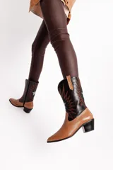 Bota tejana de cuero color marrón claro con puntera fina, caña media con bordados en negro y blanco, y taco bajo.
