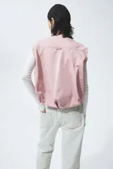Chaleco de sarga marca H&M, color rosado, con escote redondo, cierre bidireccional y bolsillos delanteros con solapa. Modelo oversized con bajo globo para una silueta abullonada.